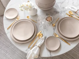 Une table dressée avec de la vaisselle NewMoon et des couverts de table dorés MetroChic Une table dressée avec des assiettes beige NewMoon et des couverts de table dorés MetroChic de Villeroy & Boch.
