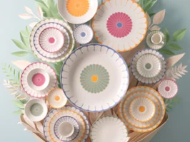 Une collection d'assiettes décoratives de la collection Fleur Une collection d'assiettes décoratives de la collection Fleur avec des motifs colorés disposés sur un mur et entourés de décorations en feuilles de papier.