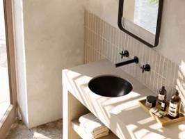Un lavabo Loop & Friends noir dans une salle de bains moderne beige Une salle de bains moderne avec un plan de toilette beige et un lavabo Loop & Friends noir. Parmi les accessoires se trouvent des serviettes et des articles de toilette.