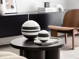 Un salon moderne avec La Boule et La petite Boule sur une table ronde foncée. Un salon moderne avec un modèle La Boule noir et blanc de Villeroy & Boch à côté de La petite Boule en noir et blanc sur une table ronde foncée.