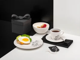 Manufacture Disney Service à petit-déjeuner dans un coffret cadeau noir Service de petit-déjeuner Manufacture Disney avec un œuf au plat sur toast, un bol de yaourt aux fruits, une tasse de thé et un coffret cadeau noir.