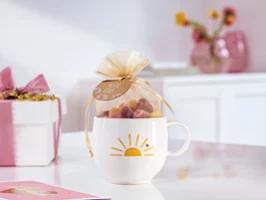 Une tasse With Love remplie de bonbons Une tasse With Love avec un soleil jaune et un motif de cœur préparé comme cadeau avec des bonbons.