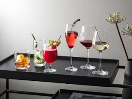 Différentes boissons dans des verres La Divina Différentes boissons dans des verres La Divina, présentées sur un plateau noir moderne, garnies d’herbes et de fruits.