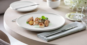 Une assiette plate blanche Afina avec un plat délicieux Une assiette Afina de Villeroy & Boch avec des échalotes et des palourdes.