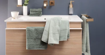 Un lavabo avec des serviettes de toilette vertes de la collection One de Villeroy & Boch et un miroir.