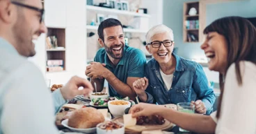 Quatre personnes riantes sont assises à une table dressée dans la salle à manger