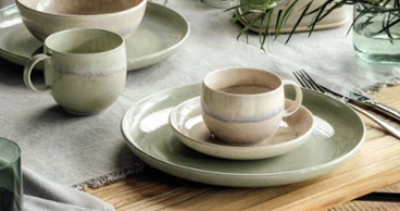 Des assiettes Perlemor vertes et beiges sur une table en bois Une décoration de table rustique avec des assiettes et des tasses Perlemor dans des tons terreux discrets sur une table en bois.