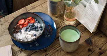 Un smoothie bowl sain sur une table en bois dans un bol Lave, un gobelet Lave avec du Matcha Latte et un menu.