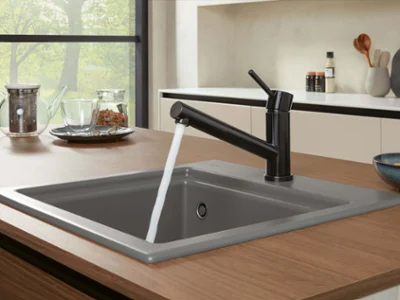 Une robinetterie Como Shower noire sur un évier de cuisine Subway Style gris avec une théière en arrière-plan.