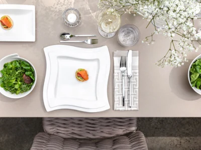 Des assiettes et des couverts de table NewWave sur une table dressée Une table dressée avec des assiettes et des couverts de table NewWave de Villeroy & Boch.