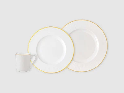 Image de la collection - Château Septfontaines Tasse blanche et deux assiettes blanches à bord doré sur fond neutre.