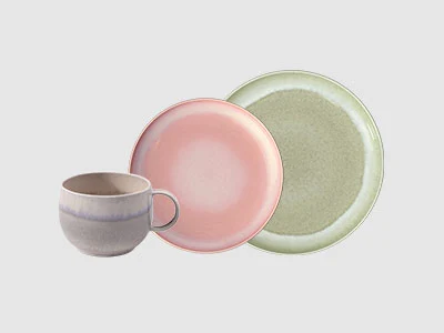 Image de la collection - Perlemor Sur un fond gris clair sont disposées une tasse grise, une assiette rose et une assiette verte.