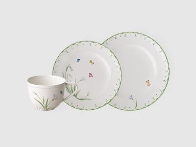 Image de la collection - Colourful Spring Tasse blanche et deux assiettes avec un bord vert et de petits motifs floraux sur un fond clair et sobre.
