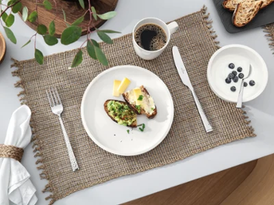 Vaisselle Artesano de Villeroy & Boch disposée sur la table du petit-déjeuner Une table dressée avec une tasse à café et une assiette Artesano blanche de Villeroy & Boch avec de la nourriture.