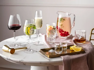 Des verres et des cruches Rose Garden sur une table ronde en marbre Des verres et des cruches de la collection Rose Garden de Villeroy & Boch sur une table ronde en marbre, avec des boissons et des agrumes.