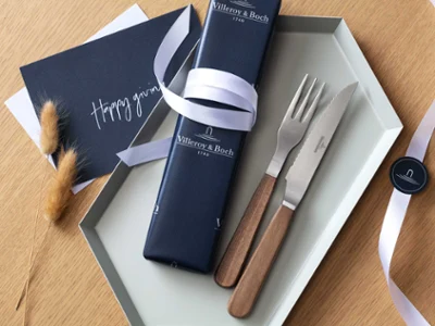 Des couverts à steak Texas en cadeau Des couverts à steak Texas de Villeroy & Boch avec un manche en bois, avec un emballage cadeau bleu et un ruban blanc.