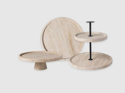 Image de la collection - Manufacture Travertine Trois plateaux de service en bois, dont un plateau rond, un présentoir à gâteaux et un présentoir à deux étages, sur un fond sobre.