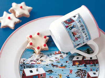 Design Naif Mug de Noël sur assiette Tasse de Noël au design naïf posée sur une assiette avec un biscuit en forme d'étoile.