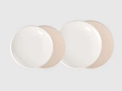 Image de la collection - NewMoon Quatre assiettes rondes en céramique, deux blanches et deux beiges, disposées côte à côte sur un fond gris clair.