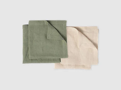 Image de la collection - Lifestyle Accessories Deux serviettes en tissu pliées, une verte et une beige, côte à côte sur un fond sobre.