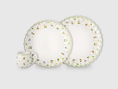 Image de collection - Easter Delight Un arrangement de deux assiettes de tailles différentes et d'une tasse, décoré d'accessoires verts et printaniers, présenté sur un fond clair.