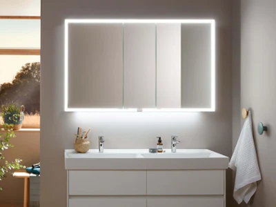Une armoire de toilette My View Now avec la lumière allumée Un lavabo de salle de bains moderne avec une armoire de toilette rétroéclairée et des accessoires bien rangés