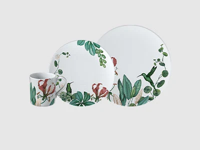Image de la collection - Avarua Set de vaisselle en céramique blanche avec des feuilles vertes et des motifs d'oiseaux rouges, composé d'une tasse, d'une petite et d'une grande assiette.