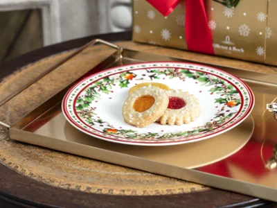 Une assiette Winter Bakery Delight de Villeroy & Boch avec des biscuits Des biscuits de Noël sur une assiette festive Winter Bakery Delight avec un cadeau en arrière-plan.