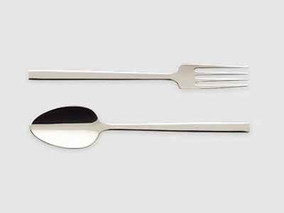 Image de la collection - La Classica Une fourchette et une cuillère en acier inoxydable sont placées côte à côte sur un fond gris clair sobre.