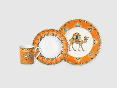 Image de la collection - Samarkand Set de vaisselle orange à motif de chameau, composé d'une tasse, d'une assiette à salade et d'une assiette plate sur fond gris.