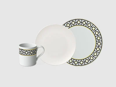 Image de la collection - MetroChic Une tasse, un bol et une assiette sont décorés d'un motif géométrique noir en bordure sur un fond gris clair.