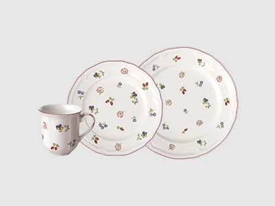 Image de la collection - Petite Fleur Une tasse blanche et deux assiettes, toutes ornées de petits motifs floraux éparpillés sur un fond clair.