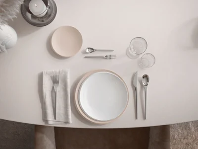De la vaisselle NewMoon élégante en beige et blanc sur une table Une table dressée avec de la vaisselle, des couverts de table et des ustensiles NewMoon dans des tons beige discrets.