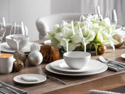 Une table élégante dressée avec la vaisselle Manufacture Une table élégante dressée avec la vaisselle Manufacture, la verrerie, l'argenterie, ainsi qu'un centre de table composé de fleurs blanches et d'ornements décoratifs.