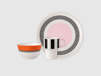 Image de la collection - Memphis Une assiette, un bol et une tasse aux motifs géométriques noirs, blancs, roses et orange sont disposés ensemble.