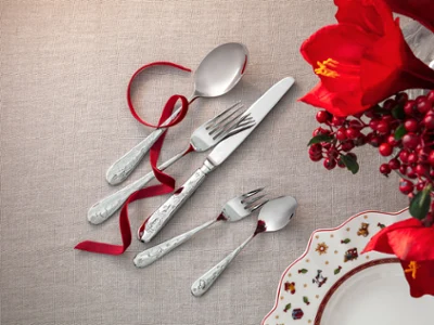 Un ensemble de couverts de table Toy’s Delight disposé sur un tissu beige avec un ruban rouge. Un ensemble de couverts de table Toy’s Delight composé d’une cuillère, d’une fourchette, d’un couteau et de deux petites cuillères, disposés sur un tissu beige avec un ruban rouge.