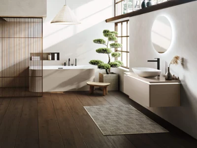 Une salle de bains minimaliste avec un sol en bois et de grandes fenêtres, une baignoire en îlot Loop & Friends, un lavabo Loop & Friends, un petit banc et un bonsaï en pot.