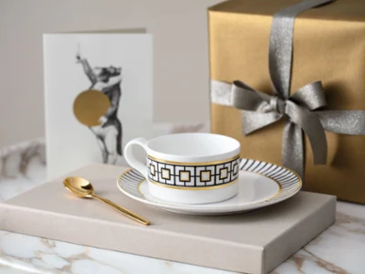 Tasse à thé MetroChic avec sous-tasse sur une table en marbre Une tasse à thé MetroChic dorée avec une sous-tasse sur une table en marbre.