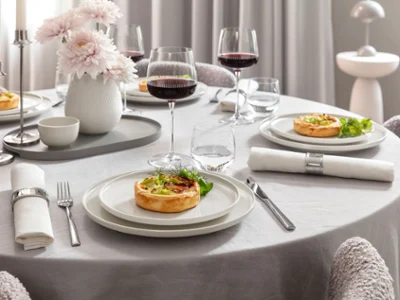 Elegant Dinner Table with Afina Porcelain & Maxima Red Wine Glasses Table élégante dressée pour quatre personnes avec vaisselle en porcelaine Afina et verres à vin rouge Maxima remplis de vin. Servie avec des plats dans une atmosphère moderne et raffinée.