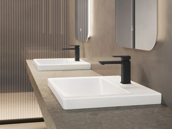 Une salle de bains moderne et minimaliste avec des murs beiges, des robinetteries noires et un plan double sous des miroirs rectangulaires. 