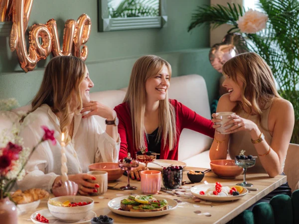 De la vaisselle Perlemor beige et des verres Like sur une table de fête Une scène festive avec trois femmes autour d’une table, avec de la vaisselle Perlemor et des verres like. by Villeroy & Boch, avec des ballons gonflés en arrière-plan.