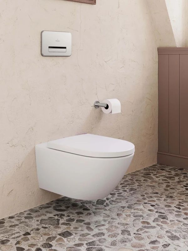 Des WC Subway 3.0 avec une plaque de déclenchement Des WC suspendus modernes avec une plaque de déclenchement dans une salle de bains aux murs structurés et au sol en pierre