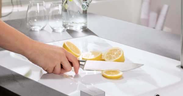 Un citron sur un évier blanc Une personne coupe des citrons dans une cuisine moderne sur un évier de cuisine blanc.