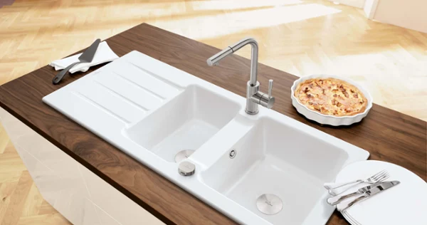 Un évier en céramique blanc Architectura sur un plan de travail en bois sur lequel est posé un gâteau.