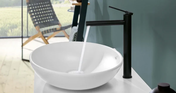Un lavabo blanc Loop&Friends avec une robinetterie Une vasque à poser Loop&Friends blanche dans une salle de bains avec un paysage en arrière-plan