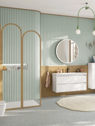 Salle de bain ludique, vert pastel avec la collection Skyla de Villeroy & Boch. Grande salle de bain familiale vert pastel avec espace douche, meuble-lavabo avec meuble bas blanc, miroir rond éclairé, meuble d'appoint, robinetterie noire et WC suspendu rectangulaire de la collection Skyla.