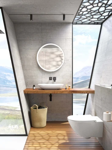 Une salle de bains moderne avec des murs en béton, grande fenêtre donnant sur un lac, un miroir rond Subway 3.0 et une vasque à poser blanche Loop & Friends