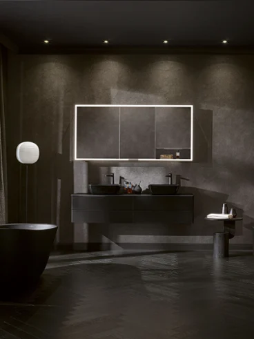 Salle de bain noire avec baignoire îlot et double vasque Salle de bain Artis entièrement noire et dramatique avec baignoire îlot, double vasque, miroir illuminé et éclairage doux pour une ambiance audacieuse et luxueuse.