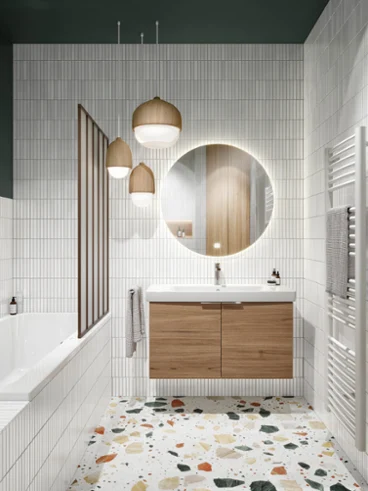 Un lavabo Architectura sur un meuble en bois à côté d’une baignoire blanche Une salle de bains avec un lavabo Architectura blanc, un meuble en bois avec un miroir rond et éclairé, des lampes suspendues et un radiateur blanc sur la droite. Sur le côté gauche se trouve une baignoire blanche avec une robinetterie grise.