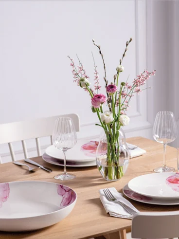Une table dressée de façon moderne pour quatre personnes avec de la vaisselle et un vase Rose Garden Une table de salle à manger moderne dressée pour quatre personnes avec une élégante vaisselle Rose Garden de Villeroy & Boch et un vase de fleurs de la collection Rose Garden.